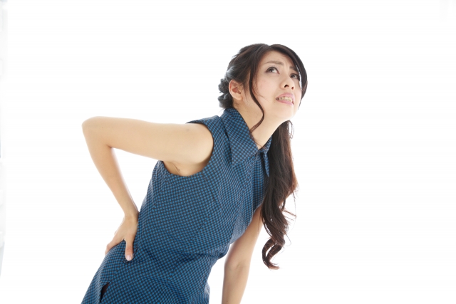腰痛で腰を押さえる女性